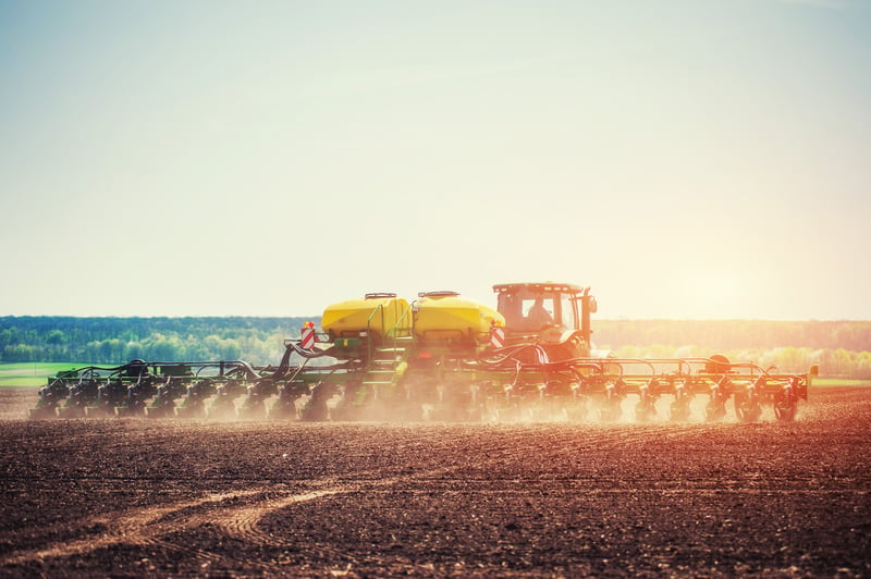 farm tractor pulling planter while seeding 